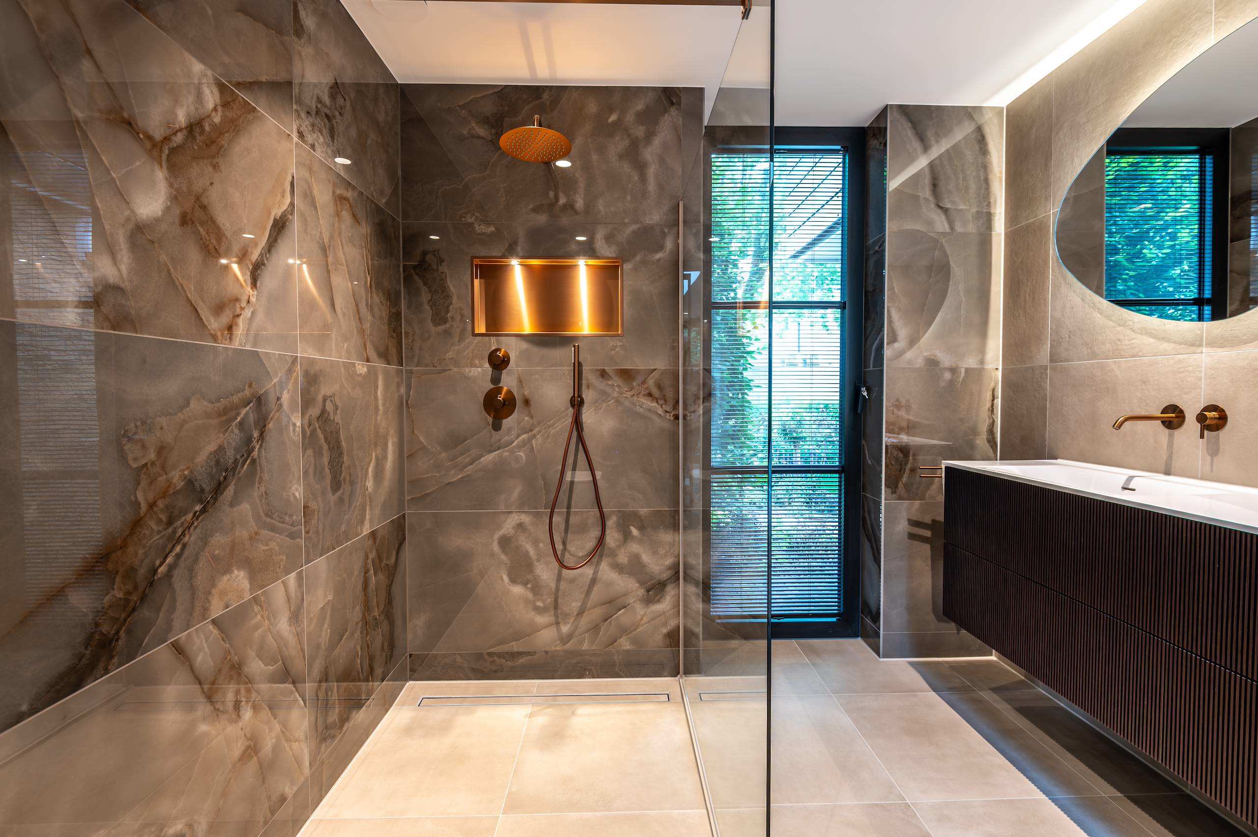 Luxe badkamer met natuursteen, regendouche en maatwerk wastafelmeubel