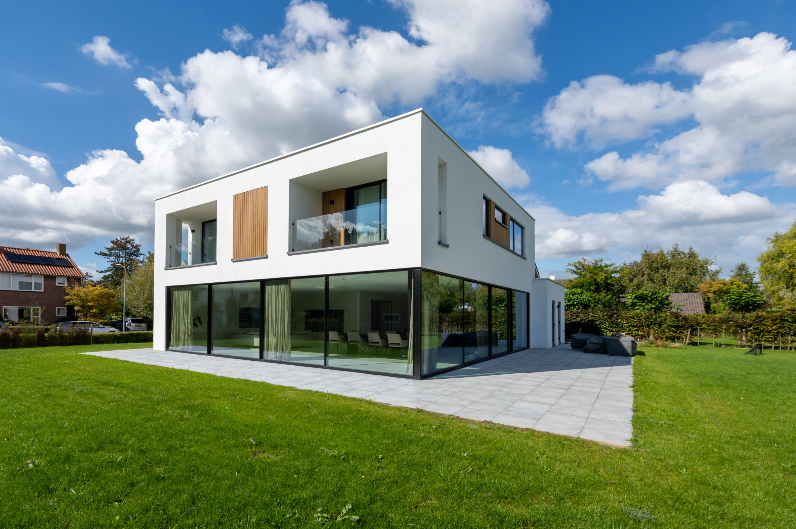 Moderne witte woning met grote glazen gevel en houten accenten