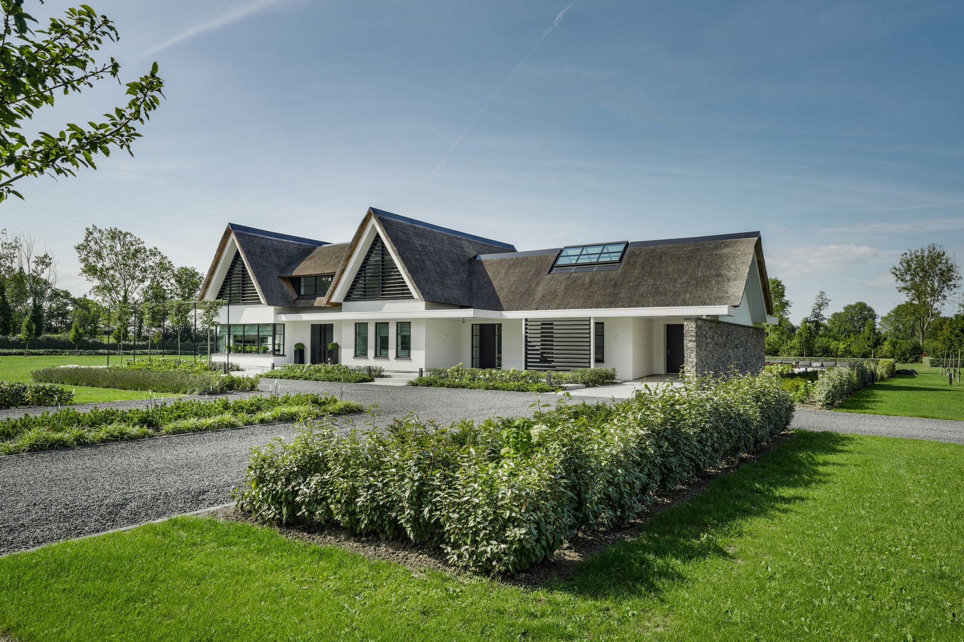 Vrijstaande woning met rieten dak in een groene tuin